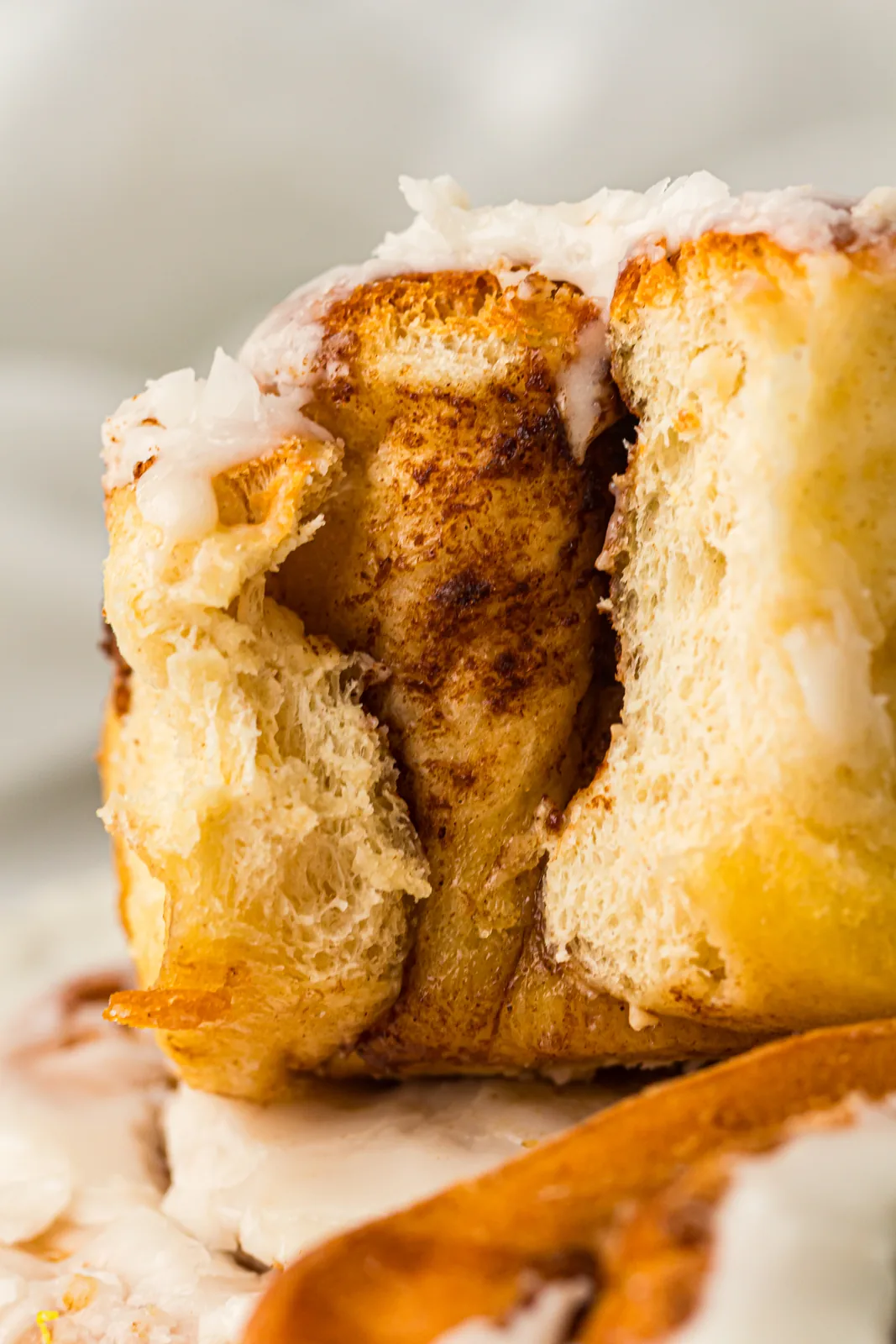 A pulled apart bun showing soft spiralled layers and white icing
