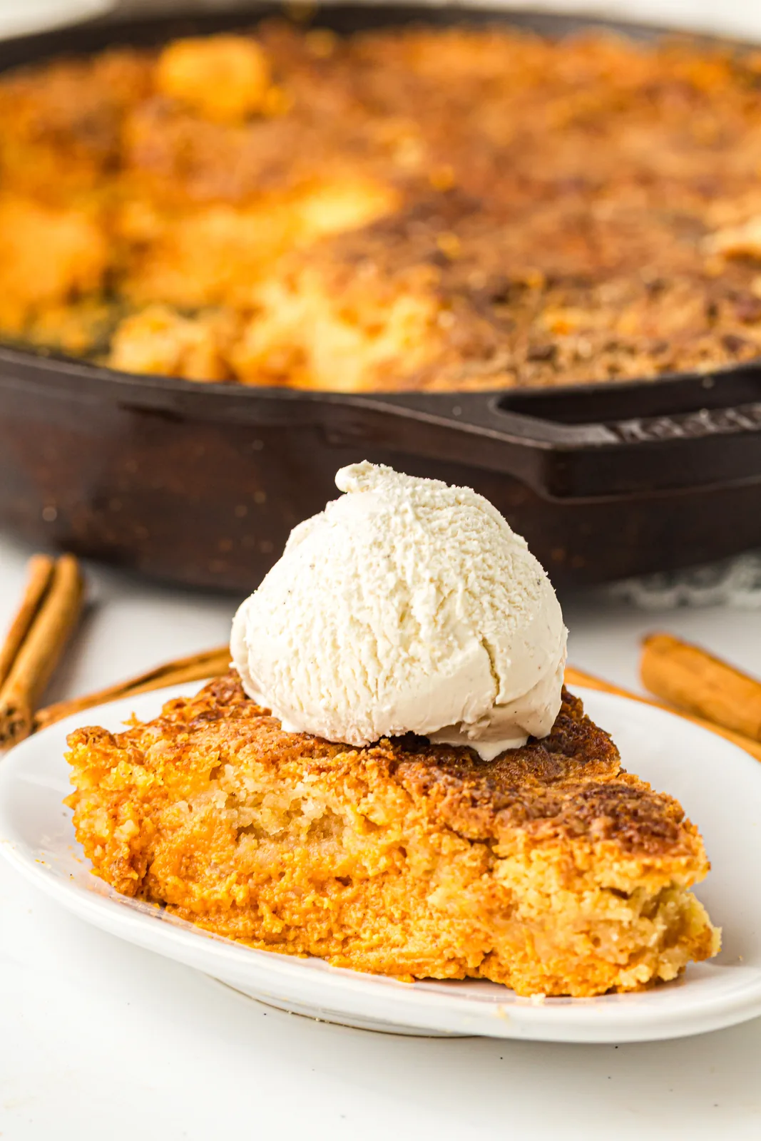 A warm serving of pumpkin dump cake with vanilla ice cream melting on top