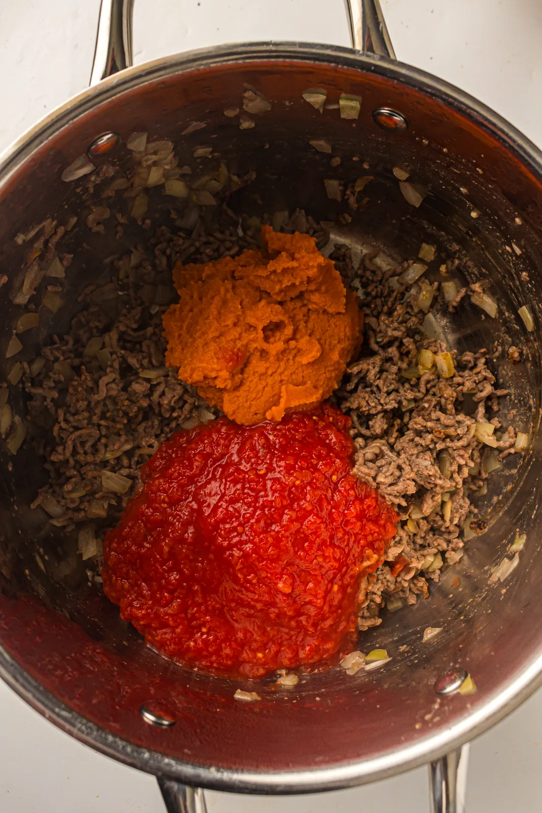 Orange purée and red tomato sauce going in on top of the browned mince
