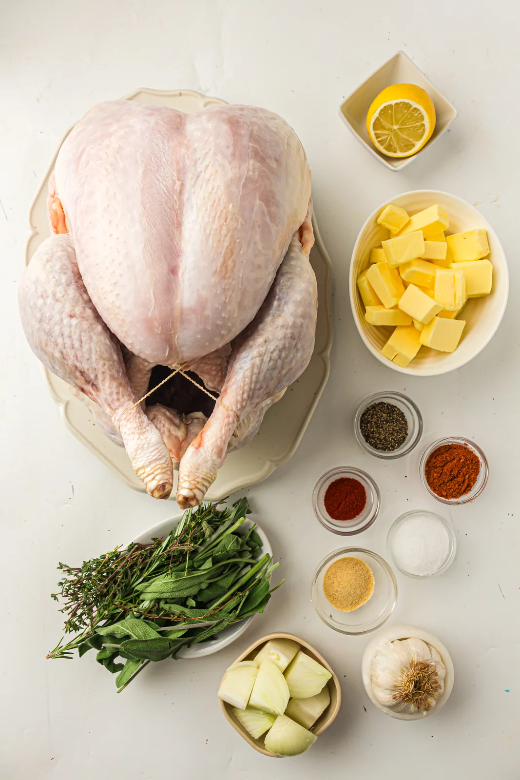 Ingredients for roast turkey: a whole bird, softened butter, spices, lemon, onion, garlic and fresh herbs