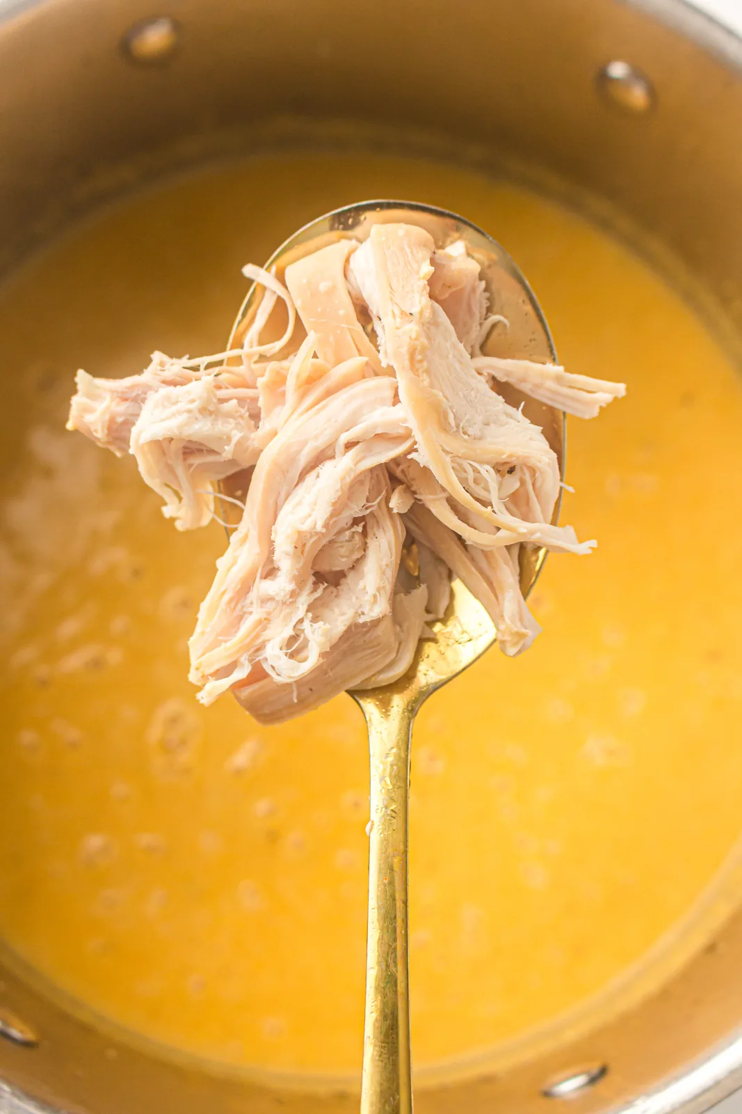 Shredded meat lifted from the pot on a slotted spoon