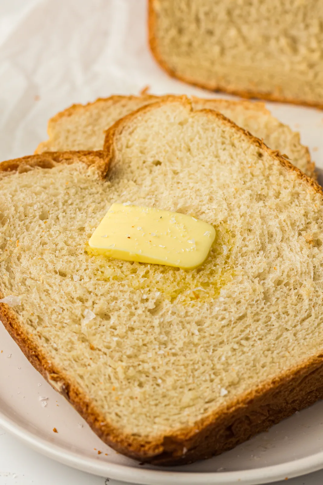 A thick slice on a plate with a pat of butter melting into it