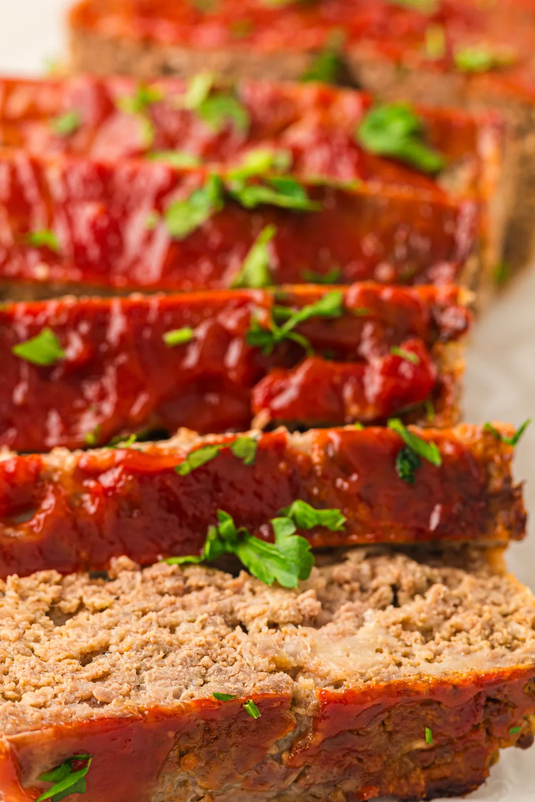 Thick slices of a glazed beef loaf fanned out on parchment