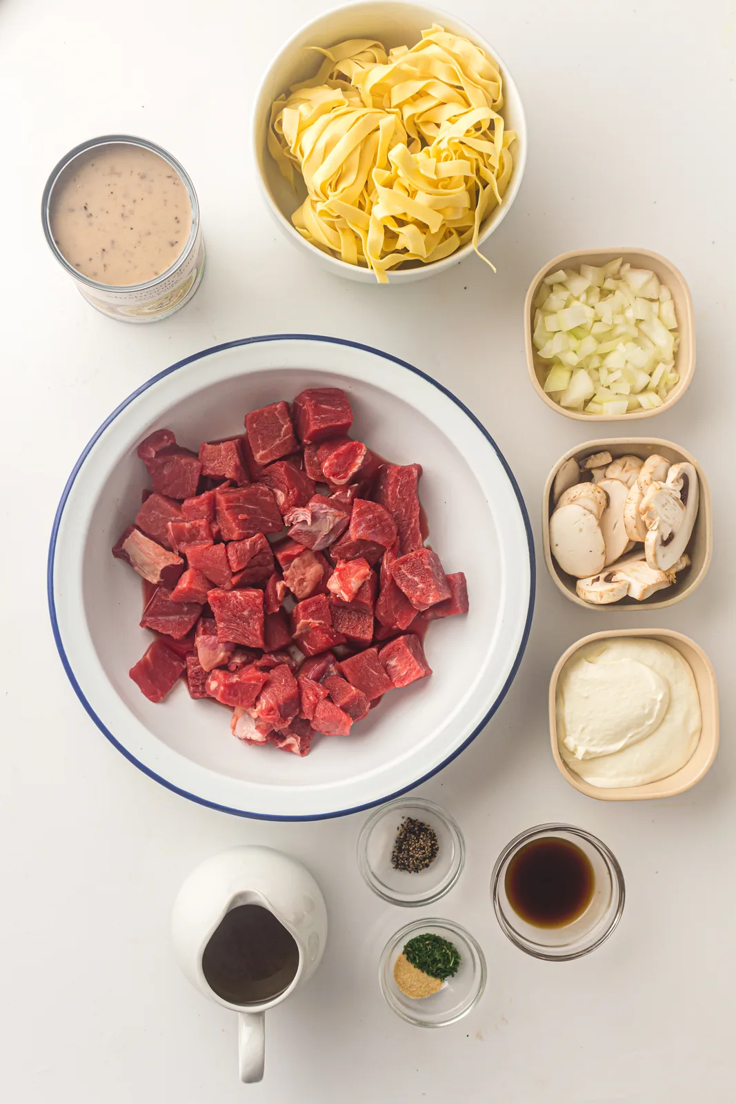 Ingredients for slow cooker beef stroganoff: cubed beef, mushrooms, onion, soup, broth and soured cream