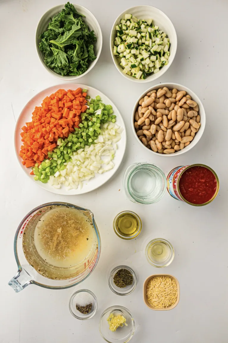 Ingredients for slow cooker minestrone soup: beans, tomatoes, carrots, celery, courgette, stock and pasta
