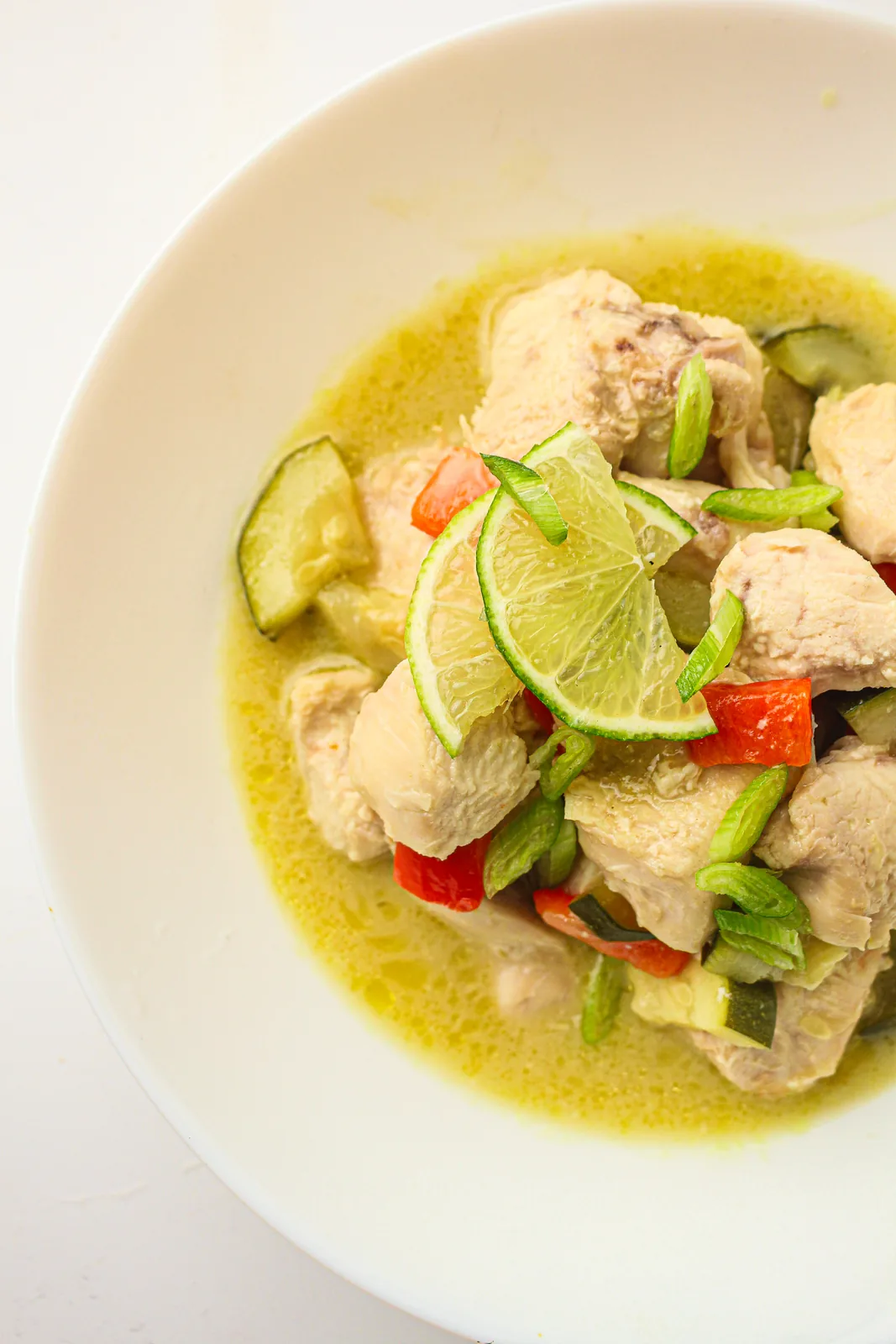 Slow cooker thai green curry in a white bowl with lime and red pepper