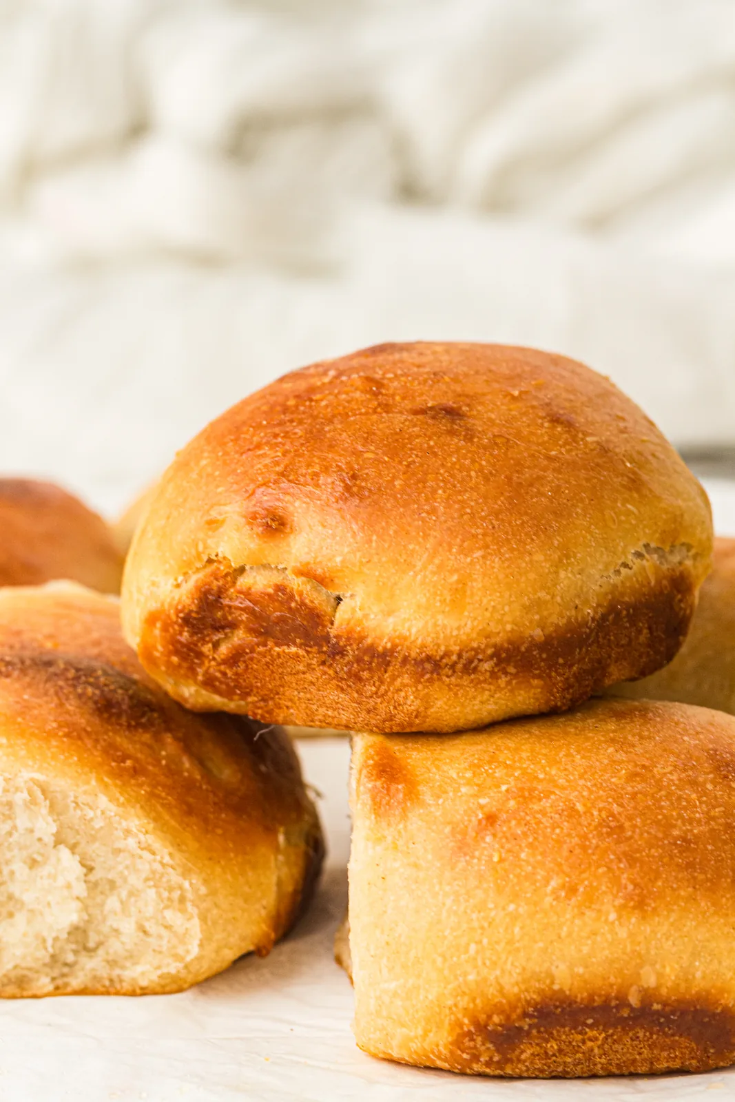 Golden sourdough dinner rolls stacked on a linen cloth