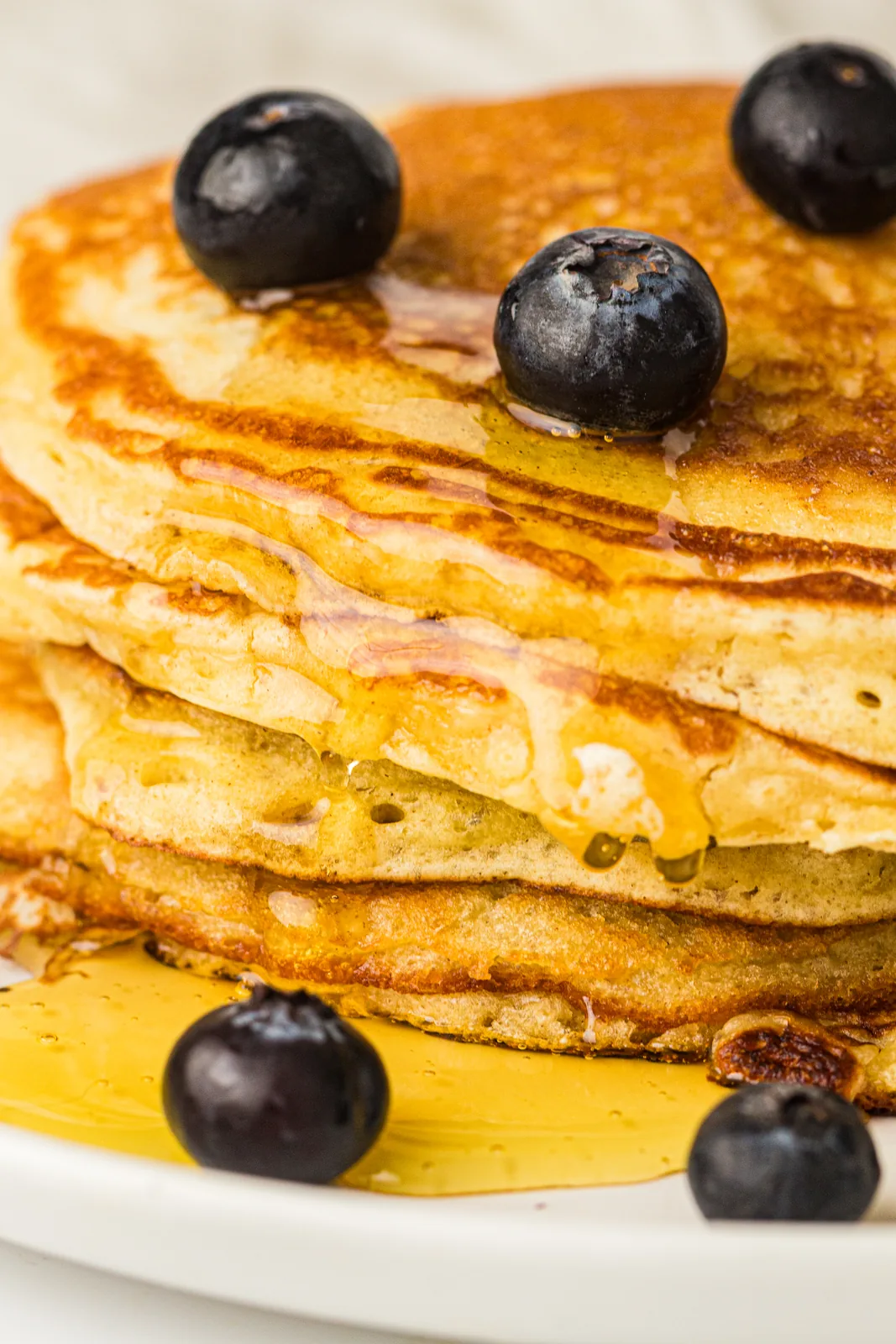 A tall stack of sourdough discard pancakes with maple syrup and blueberries