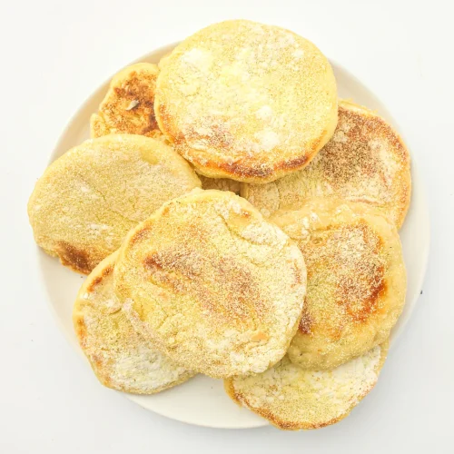 Sourdough english muffins dusted with semolina on a white plate