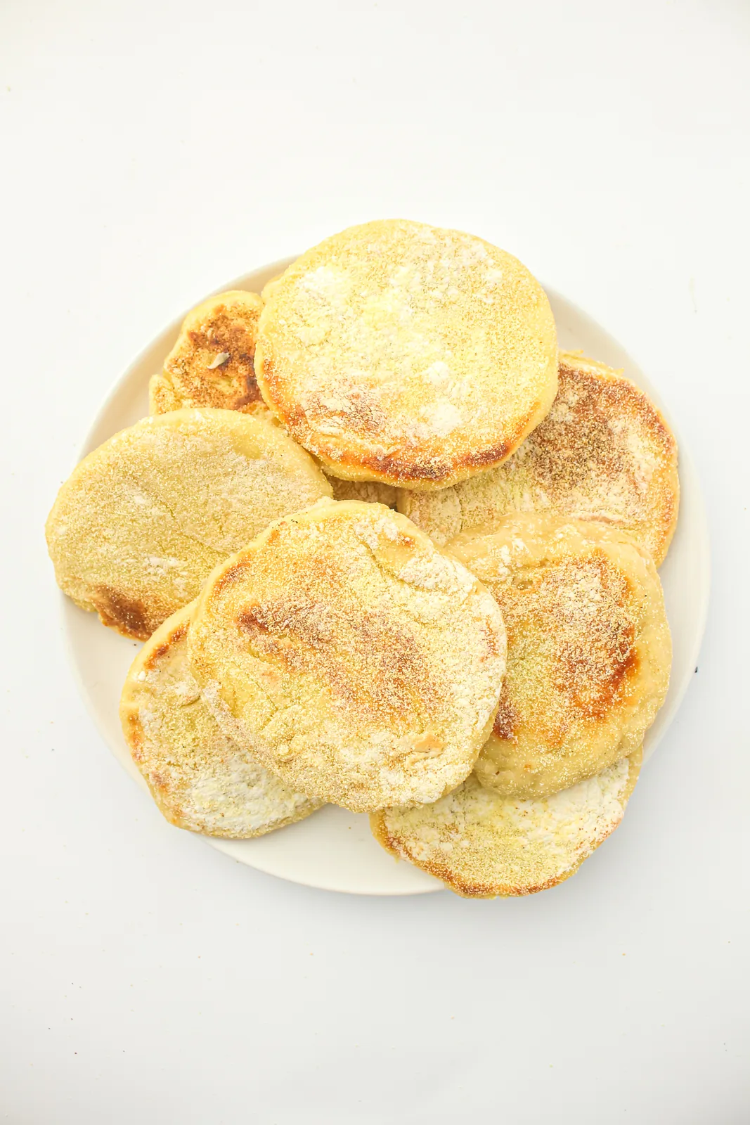Sourdough english muffins dusted with semolina on a white plate