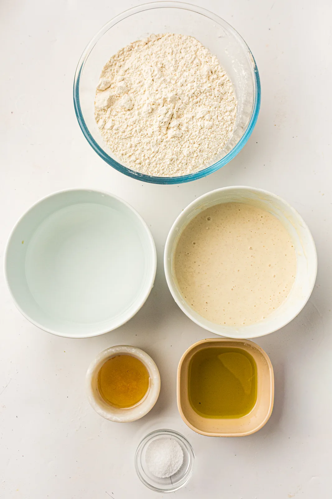 Ingredients for sourdough pizza dough: starter, bread flour, water, olive oil and salt