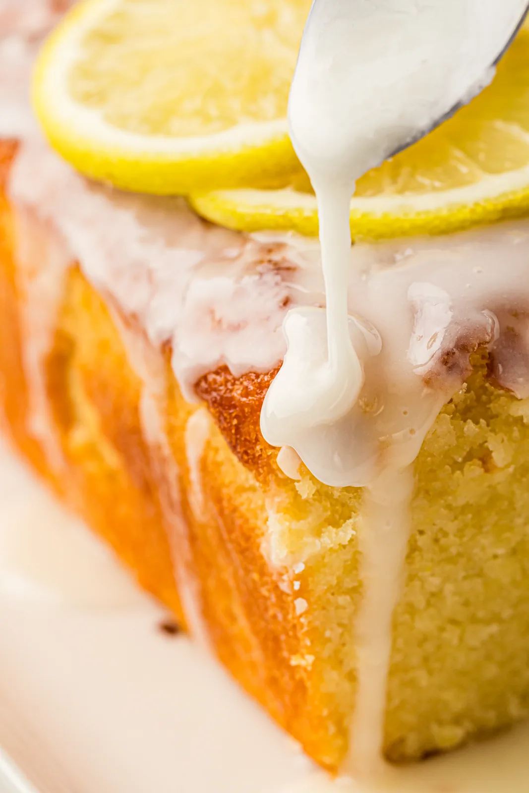 Thick white icing being spooned over the cooled loaf