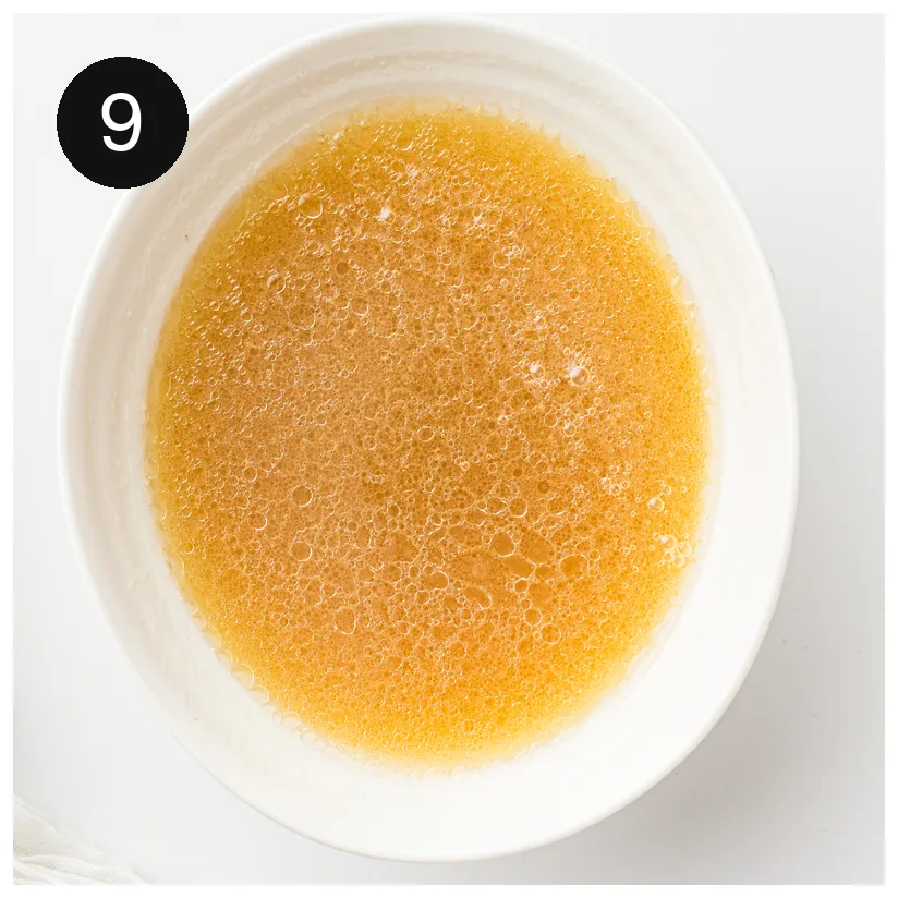 The finished golden broth in a shallow white bowl