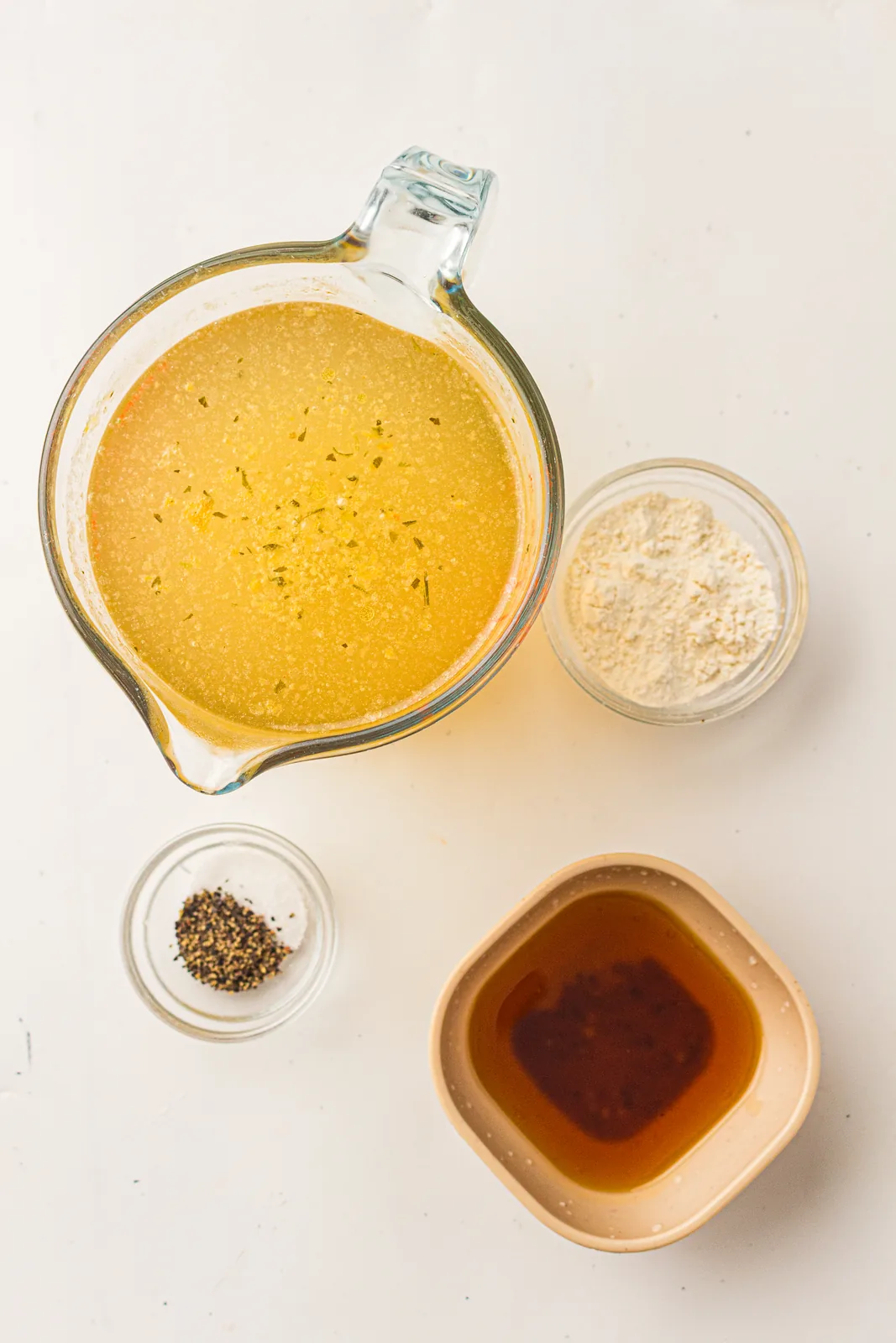 Ingredients for turkey gravy: a jug of stock, pan drippings, plain flour and black pepper