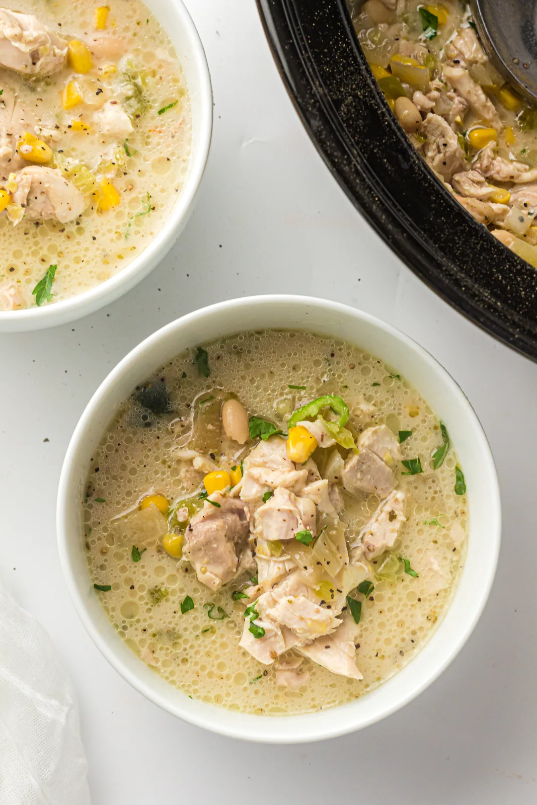 Two bowls of the creamy pale stew beside the slow cooker
