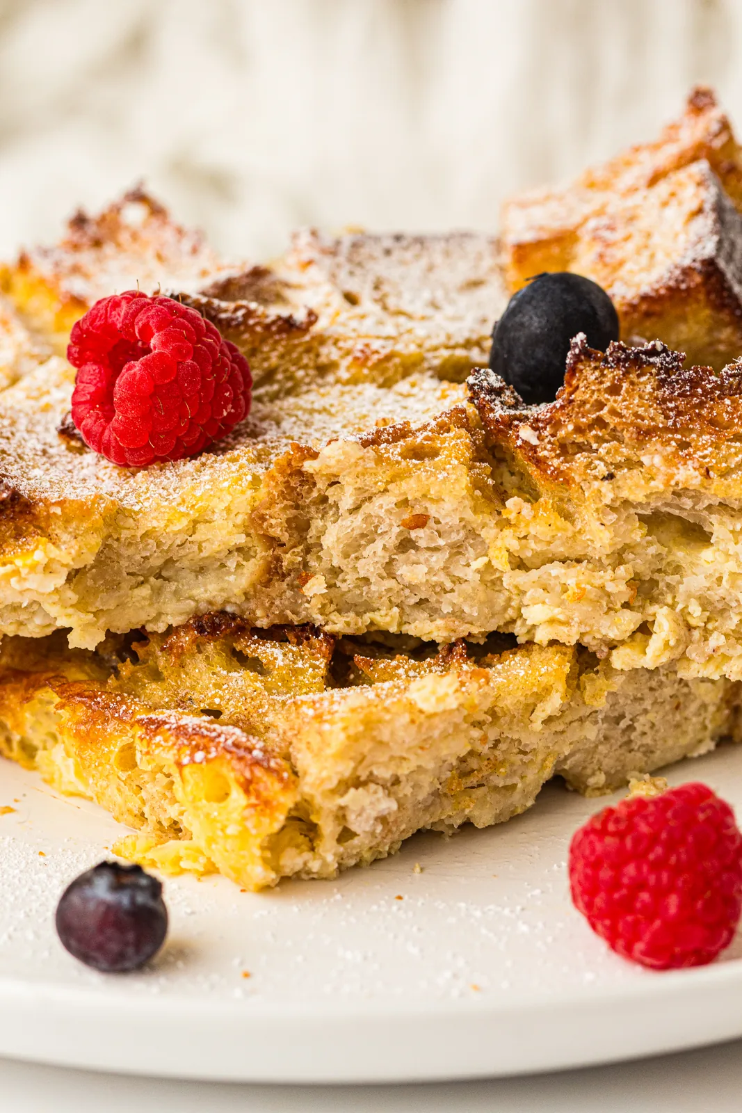 Two golden squares dusted with icing sugar on a pale plate