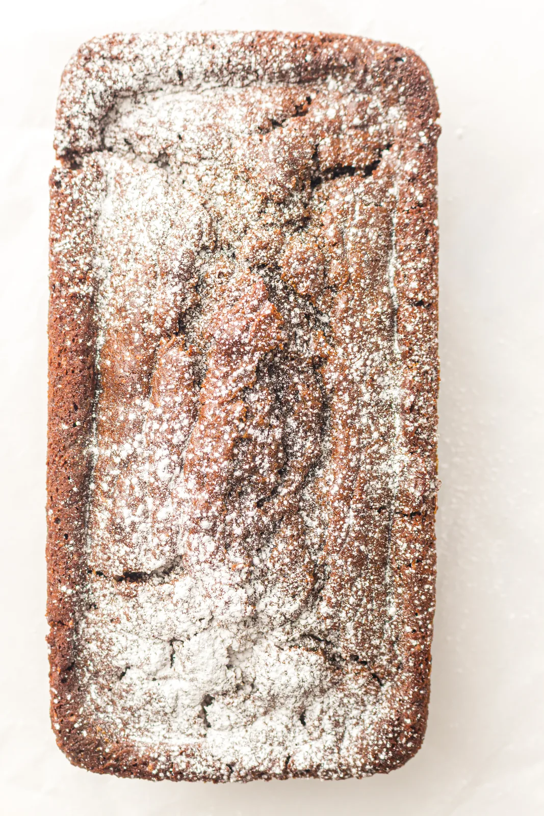 The whole dusted cake photographed from above on parchment