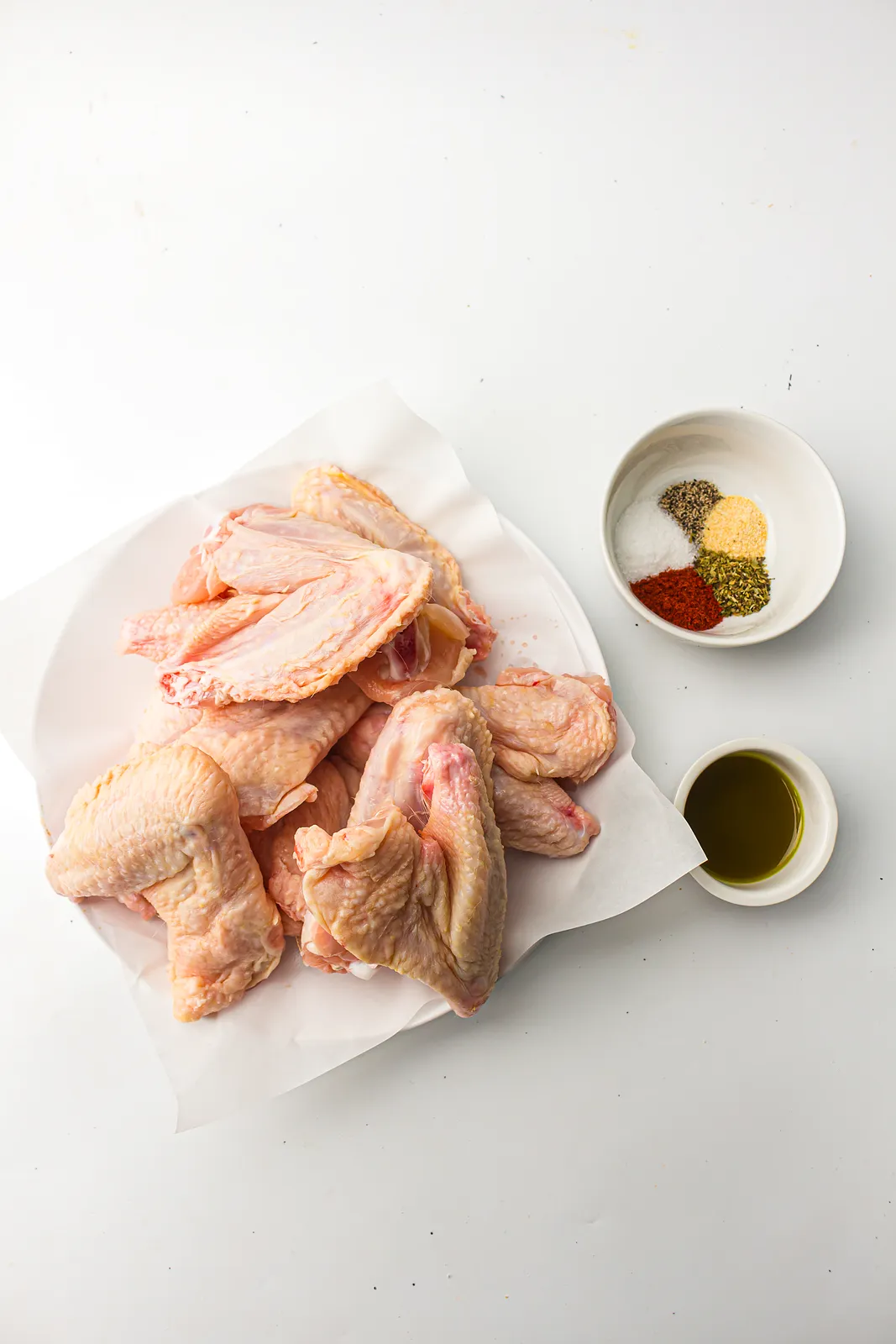 Ingredients for air fryer chicken wings: raw wings, avocado oil, salt, pepper, garlic powder, paprika and herbs
