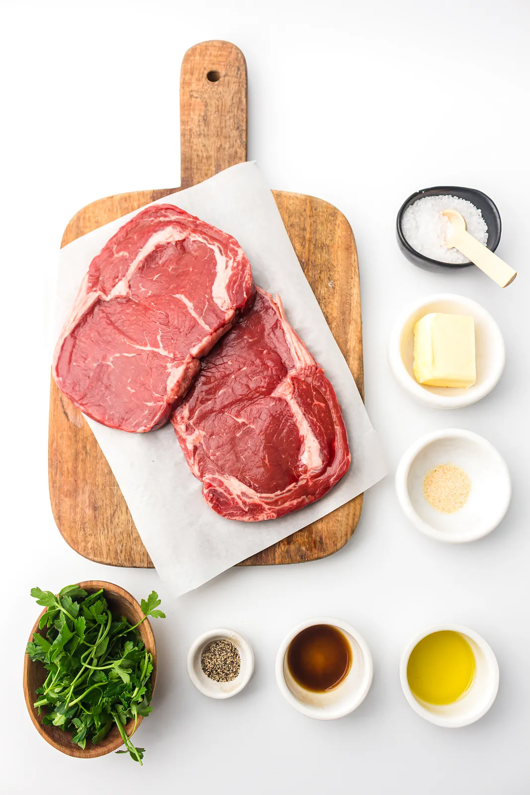 Ingredients for air fryer steak bites: ribeye steaks, butter, parsley, salt, pepper, garlic powder, Worcestershire sauce and oil