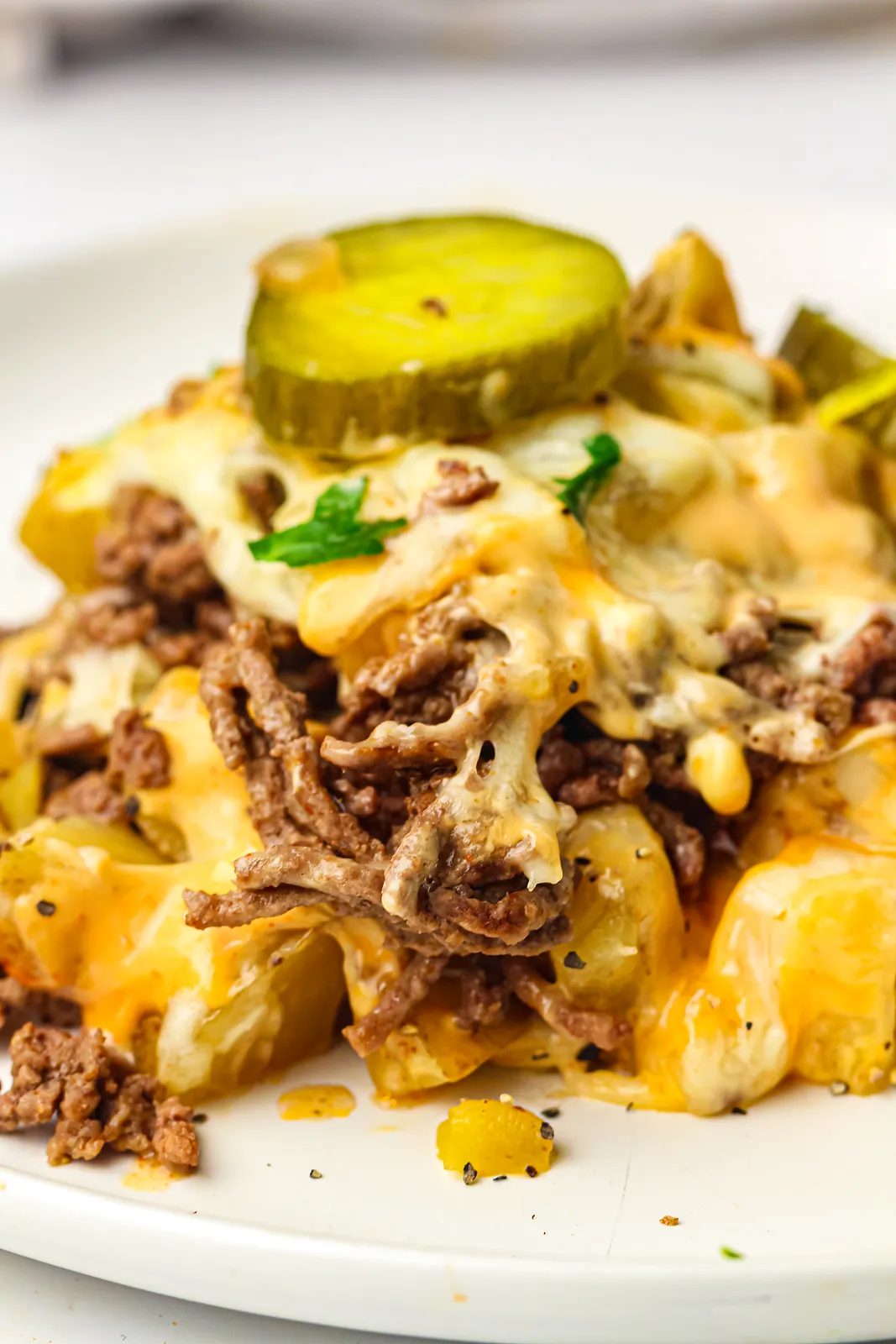Beef and potato hash on a plate topped with a pickle slice and melted cheese