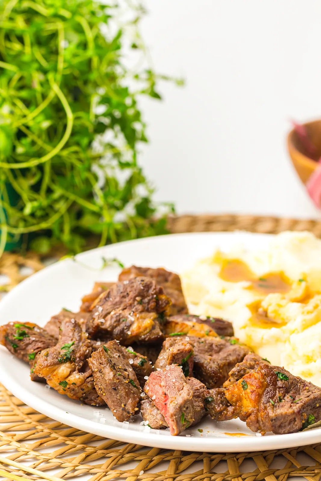 Buttery beef cubes served on a plate beside a mound of creamy mashed potatoes