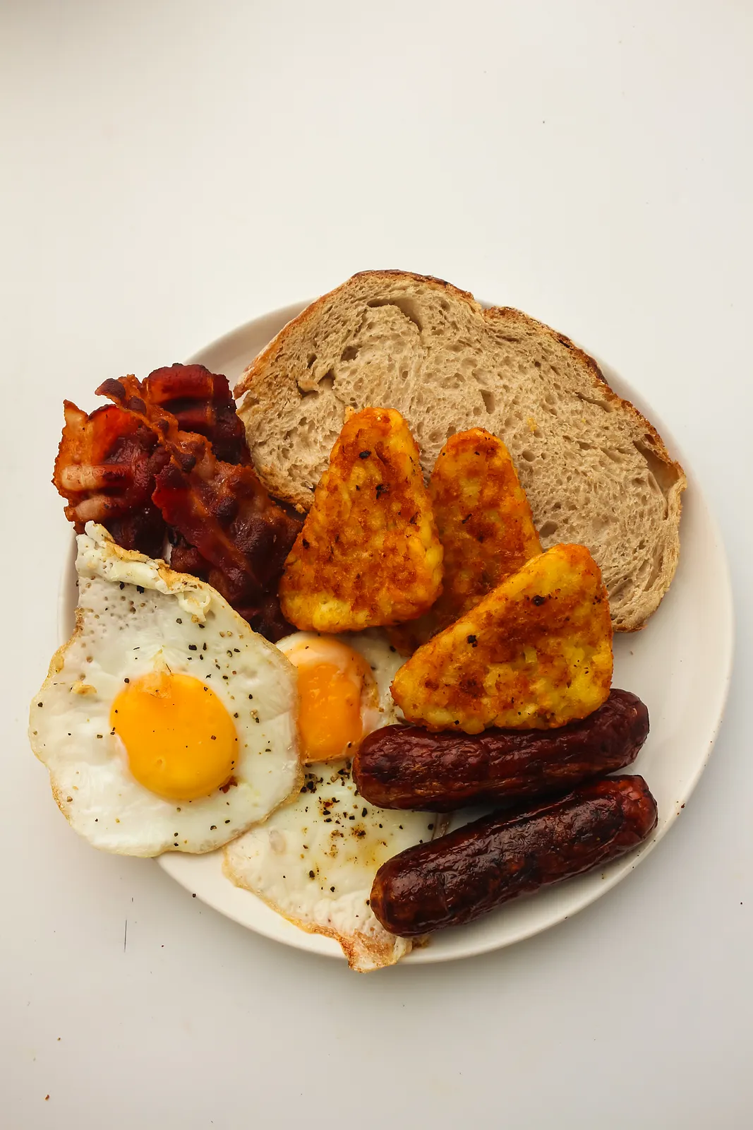 Blackstone breakfast plate with crispy bacon, sausages, hash brown triangles, a fried egg and toast