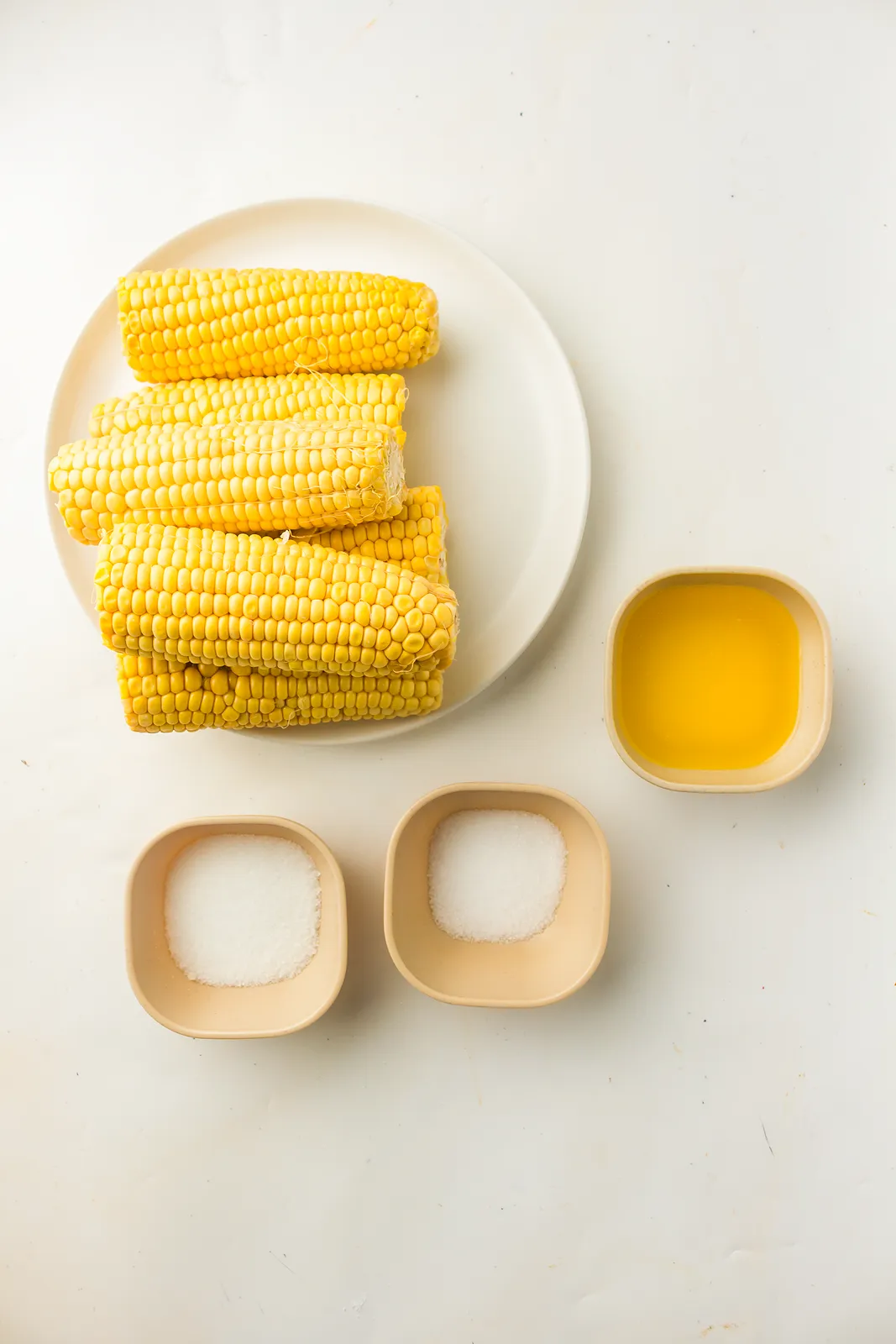 Ingredients for boiled corn on the cob: husked ears, melted butter, salt and sugar
