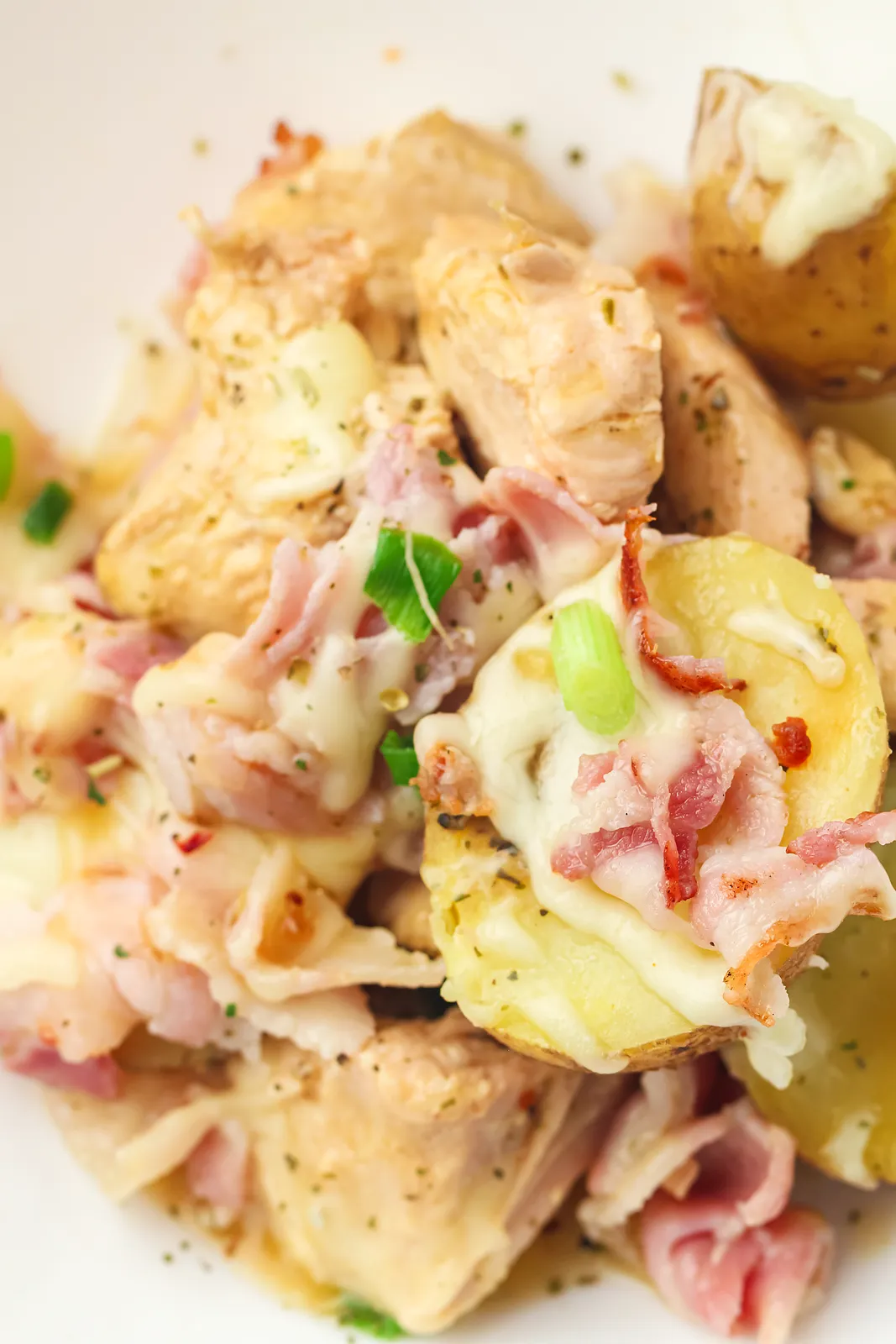 Close up of a bowl piled with tender potatoes, melted cheese and herbs