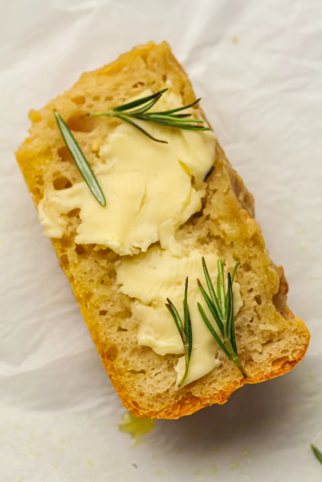 A thick slice spread with soft butter and topped with rosemary sprigs