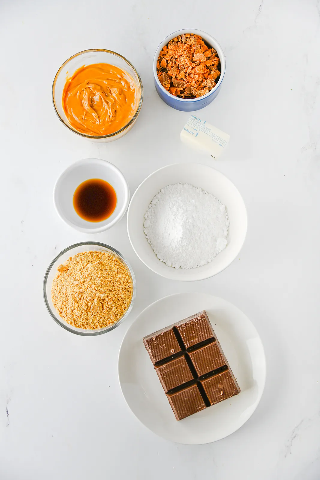 Ingredients for butterfinger balls: peanut butter, butter, vanilla, powdered sugar, graham crumbs, crushed candy and almond bark