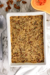 Butternut squash casserole with a pecan crumble topping in a white baking dish