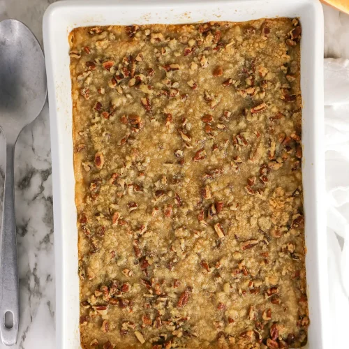 Butternut squash casserole with a pecan crumble topping in a white baking dish