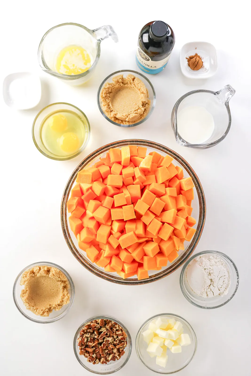 Ingredients for butternut squash casserole: cubed squash, eggs, brown sugar, butter, milk, vanilla, cinnamon, flour and pecans