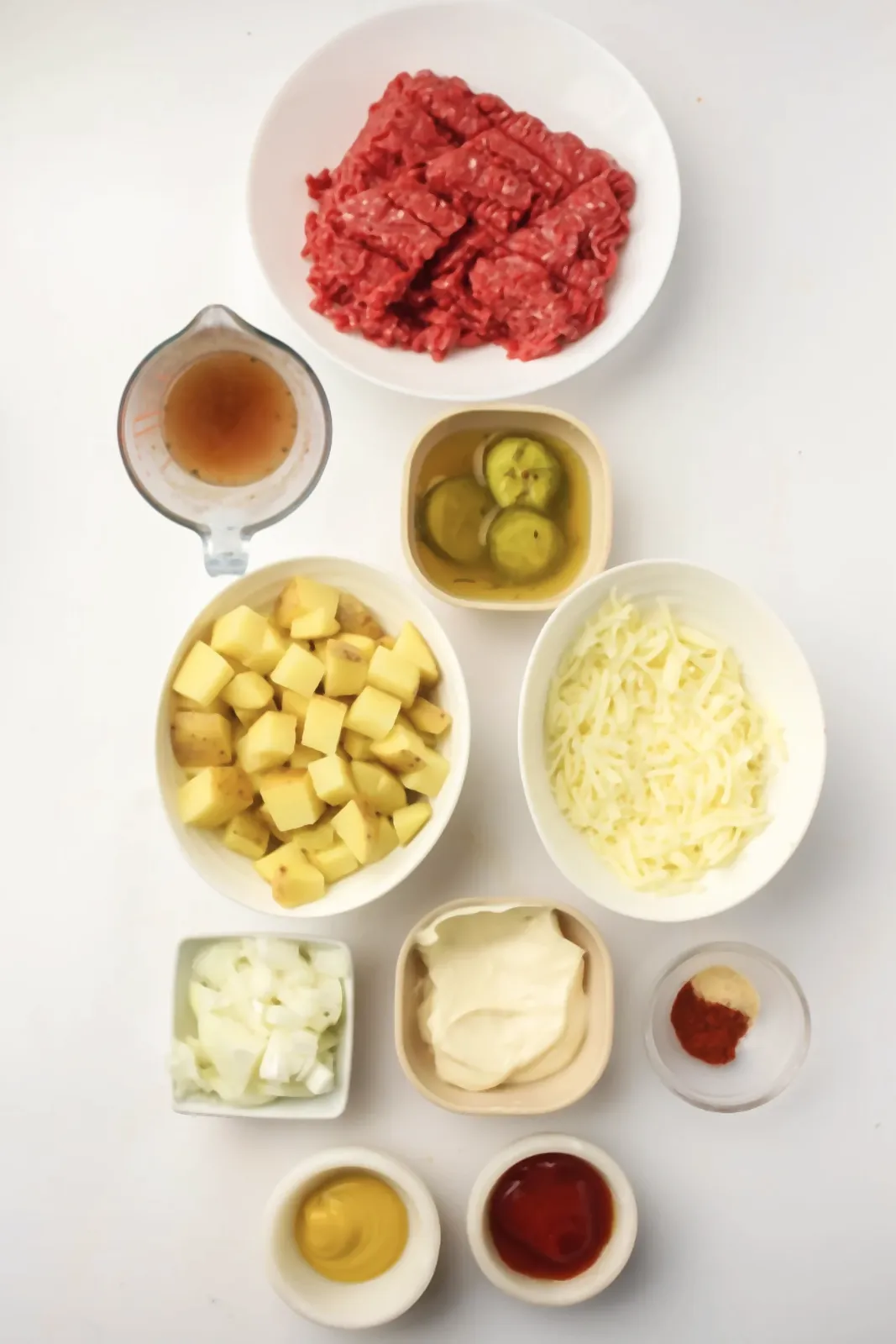 Ingredients for a cheeseburger skillet: beef mince, diced potatoes, onion, stock, cheese, pickles, mayonnaise, ketchup and mustard