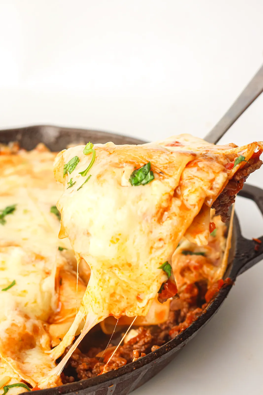 A cheesy wedge lifted from the cast iron pan with a long stretch of melted mozzarella