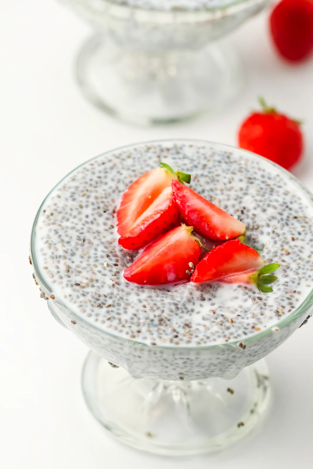Chia pudding in a footed glass topped with sliced strawberries