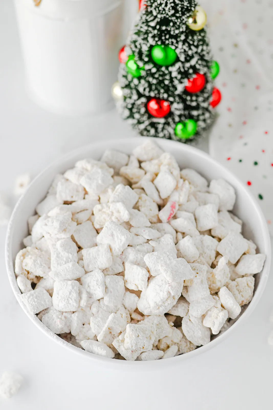 Christmas snack mix bowl with a bottle brush tree and polka dot napkin