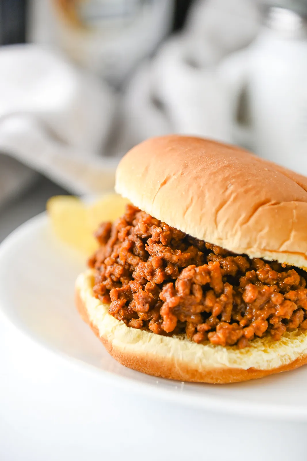 Close up of saucy ground beef spilling out of a soft burger bun