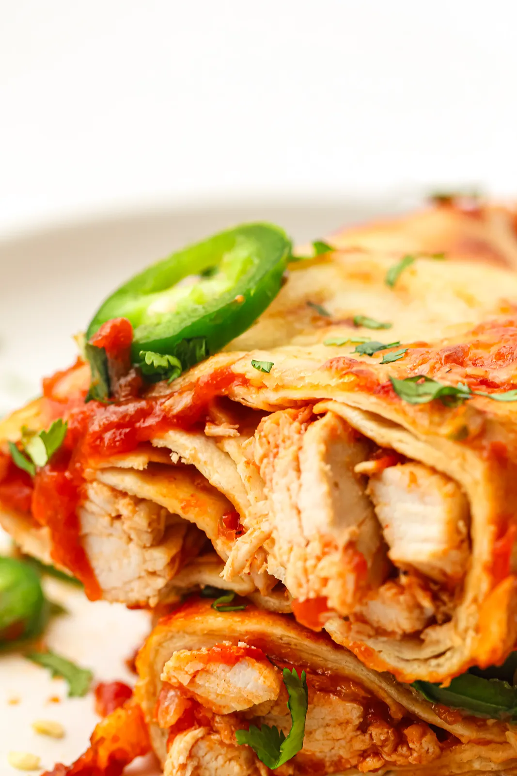 Close up of saucy shredded chicken inside soft baked tortillas