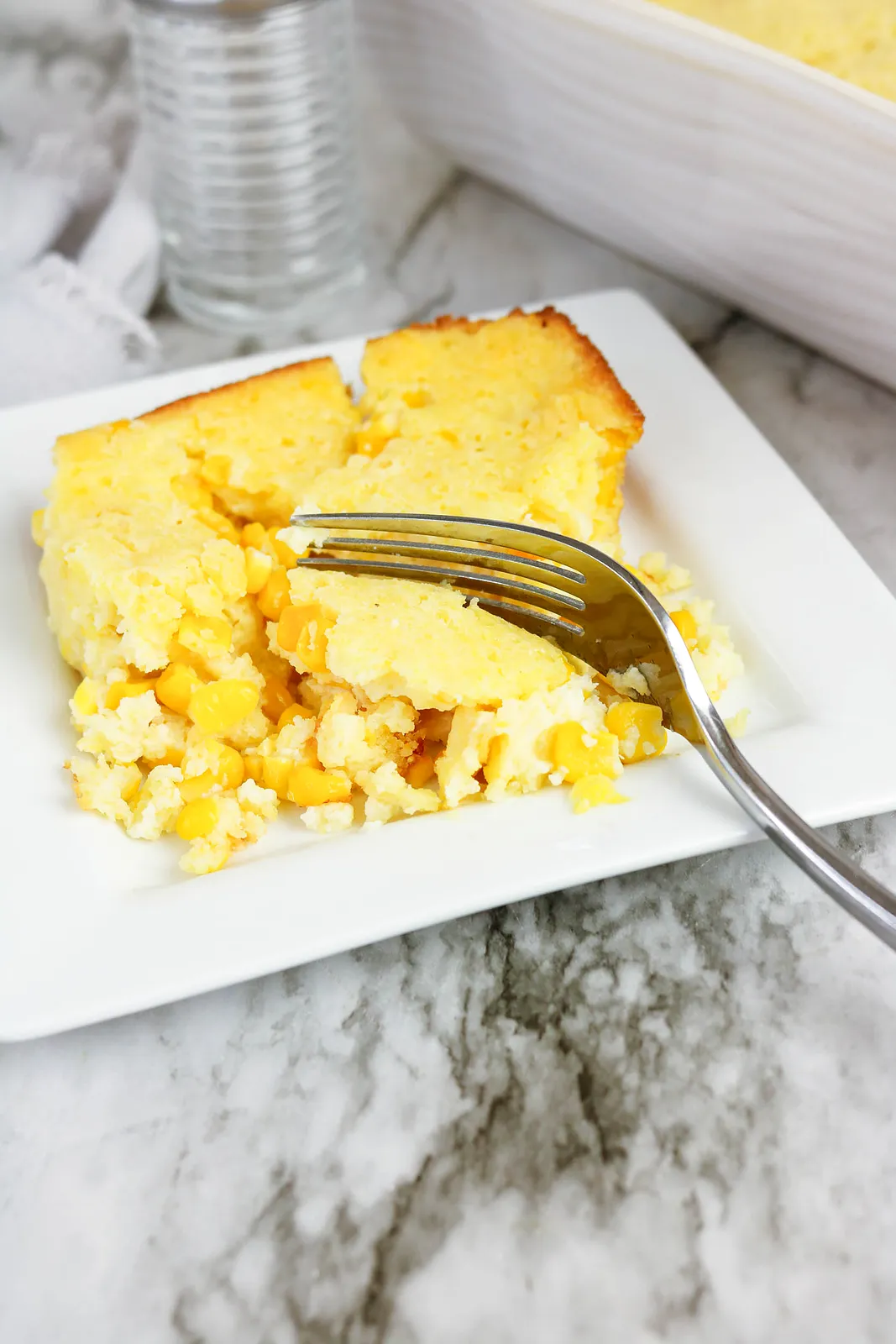 A fluffy yellow square on a white plate with a fork cutting through the tender middle