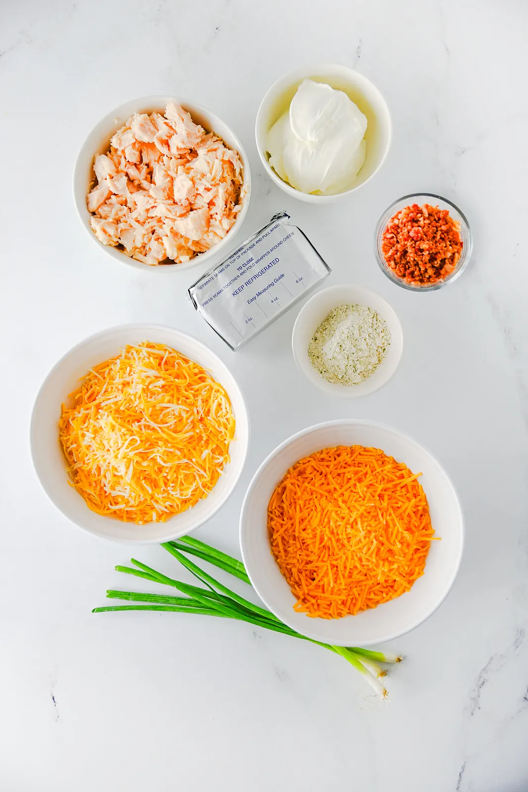 Ingredients for crack chicken dip: canned chicken, cream cheese, sour cream, ranch seasoning, bacon, Colby jack, cheddar and green onions