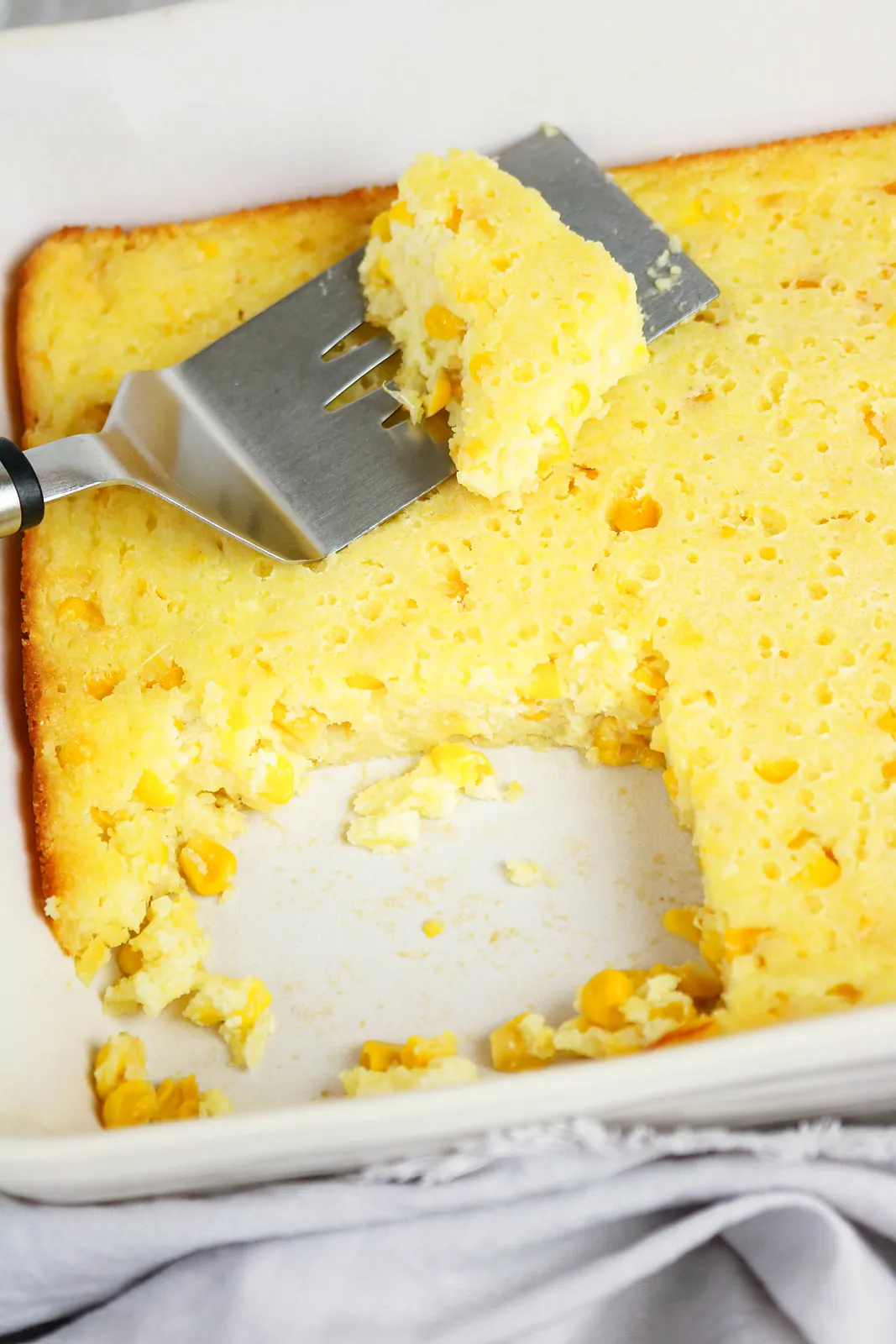 A golden sweetcorn bake with one serving lifted out, showing the creamy kernel-studded centre
