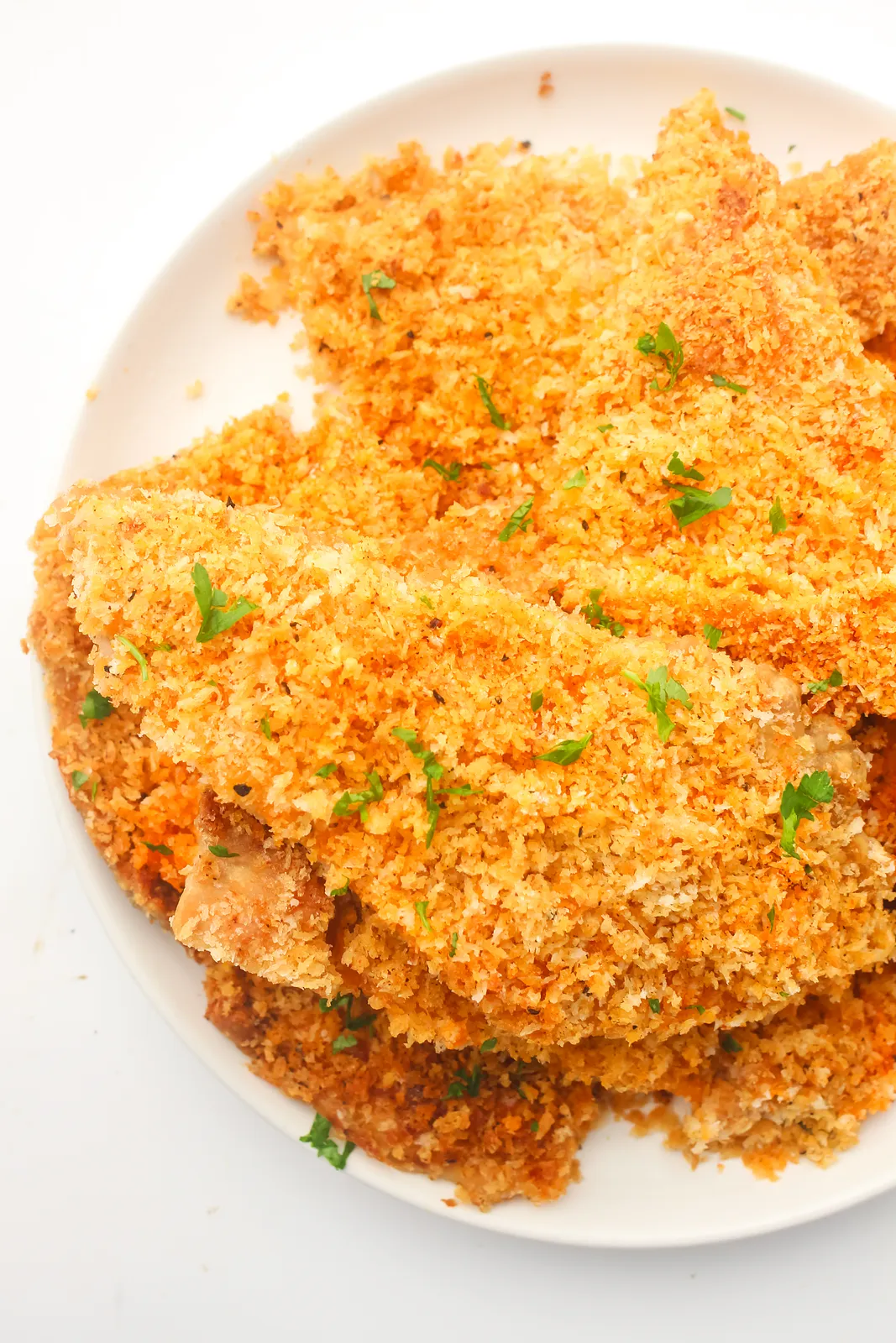 Crispy golden crumbed slices piled high on a white plate