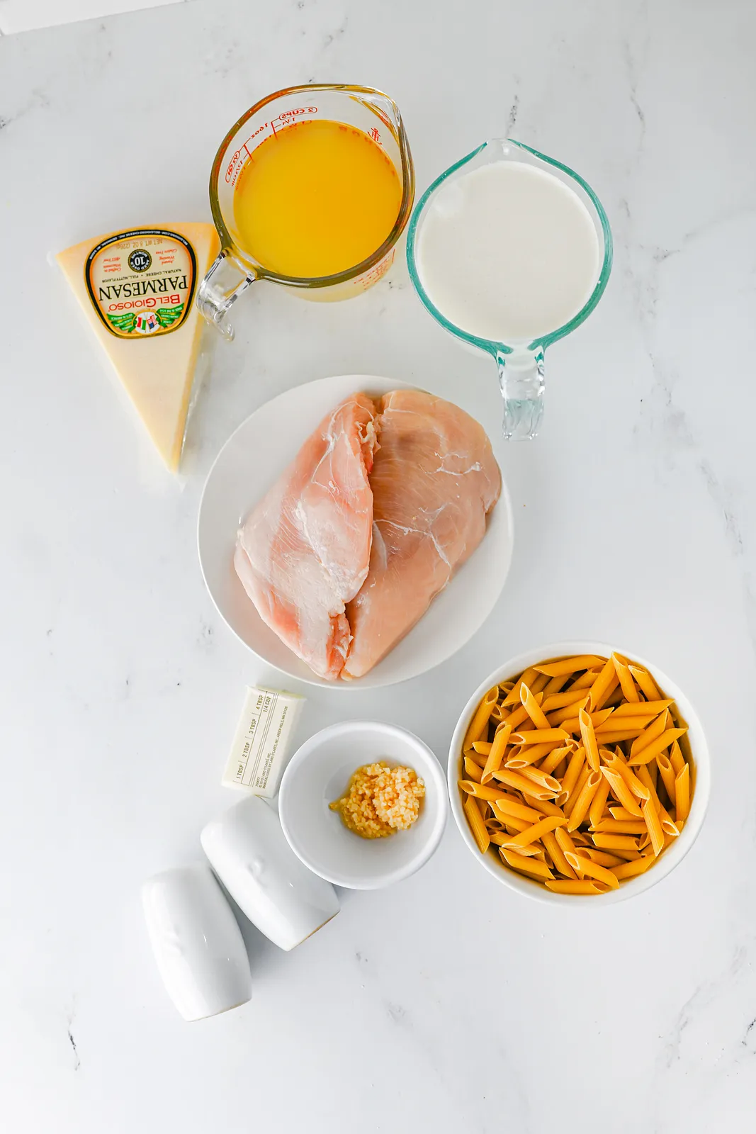Ingredients for crockpot chicken alfredo: chicken breasts, broth, cream, Parmesan, butter, garlic and dry penne