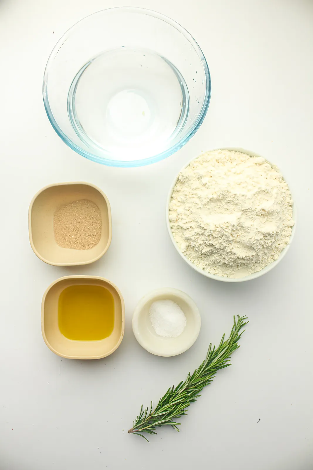 Ingredients for crockpot focaccia bread: bread flour, instant yeast, warm water, olive oil, salt and a rosemary sprig
