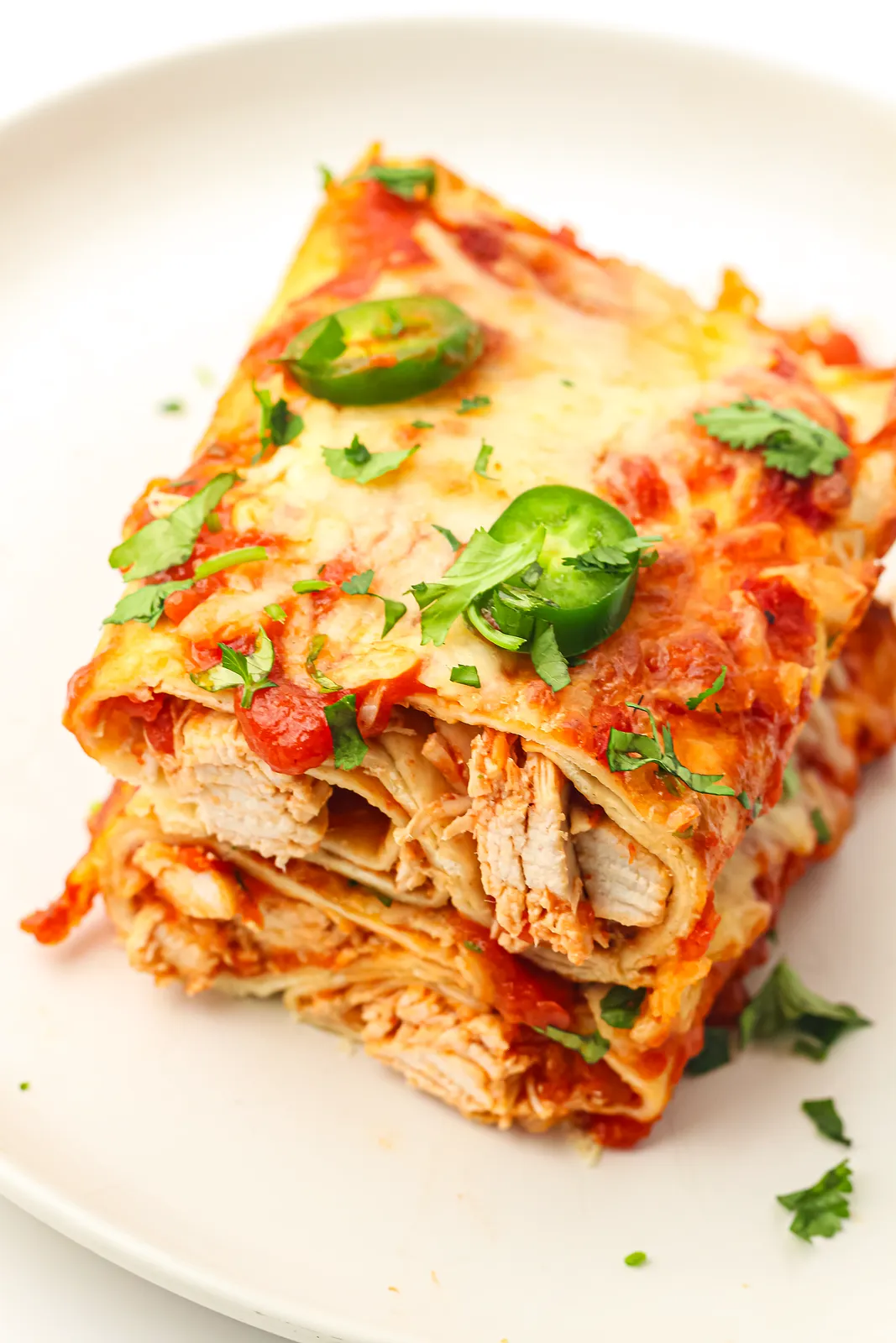 A cut tortilla roll showing tender shredded chicken, topped with jalapeño