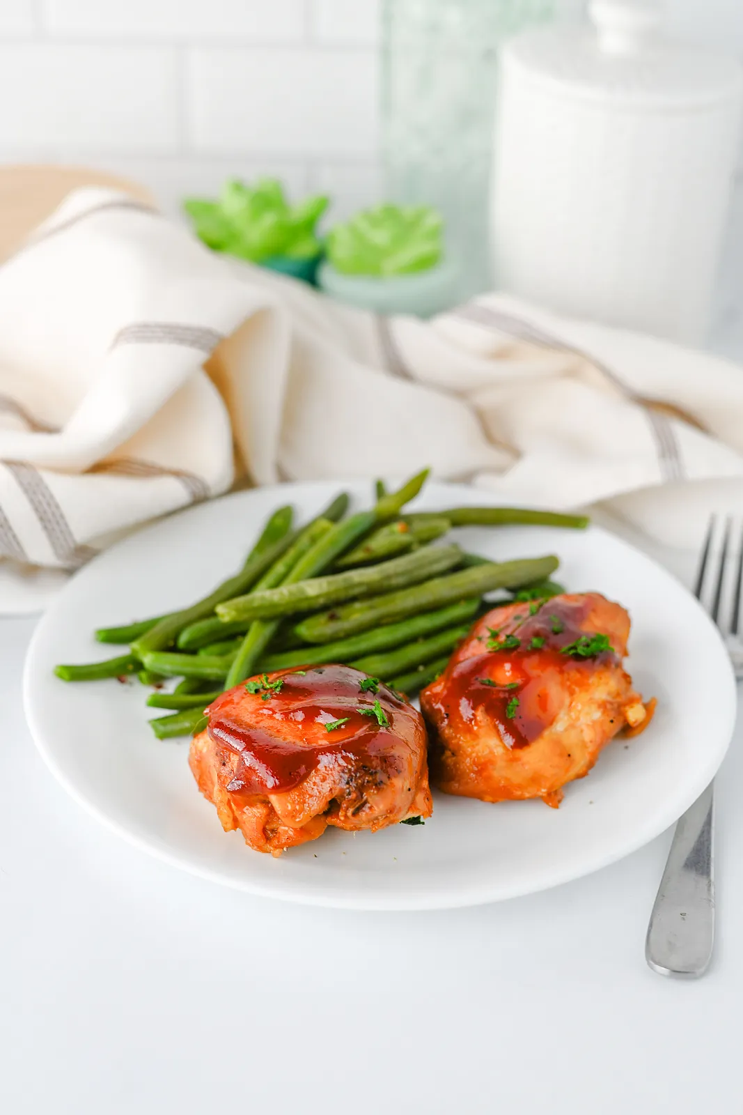 Two saucy glazed pieces served with buttery green beans and a fork