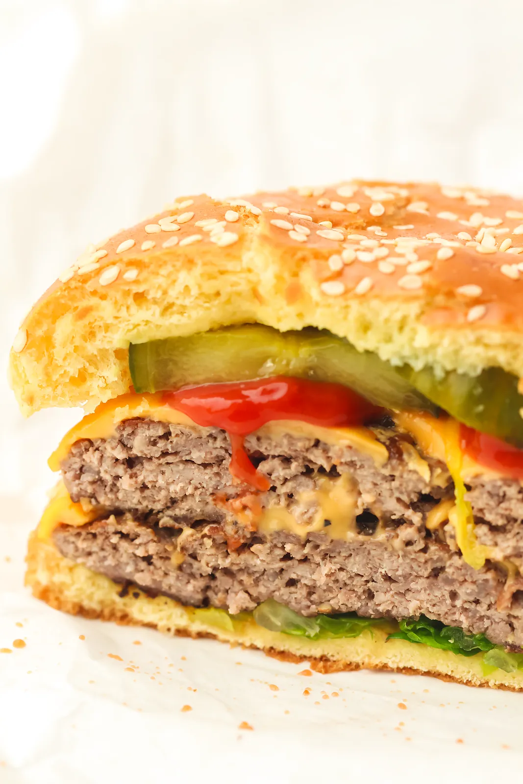 Side view of a double patty cheeseburger with pickles and ketchup