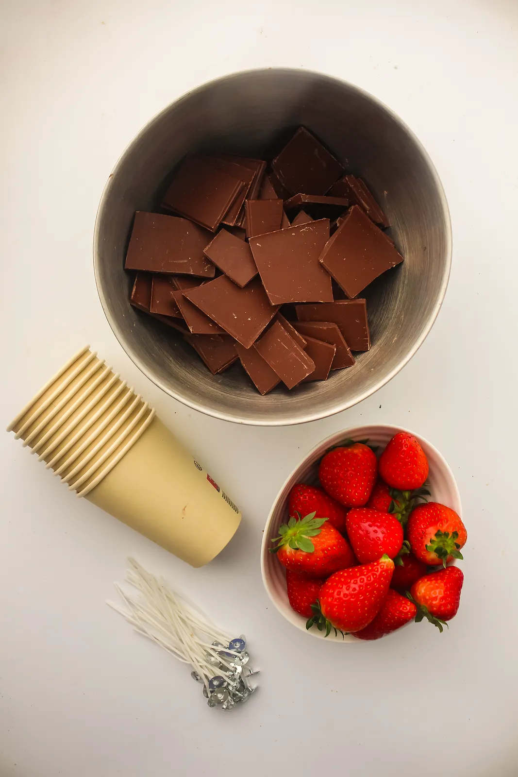 Ingredients for edible chocolate candles: milk chocolate, paper cups, food-grade wicks and strawberries