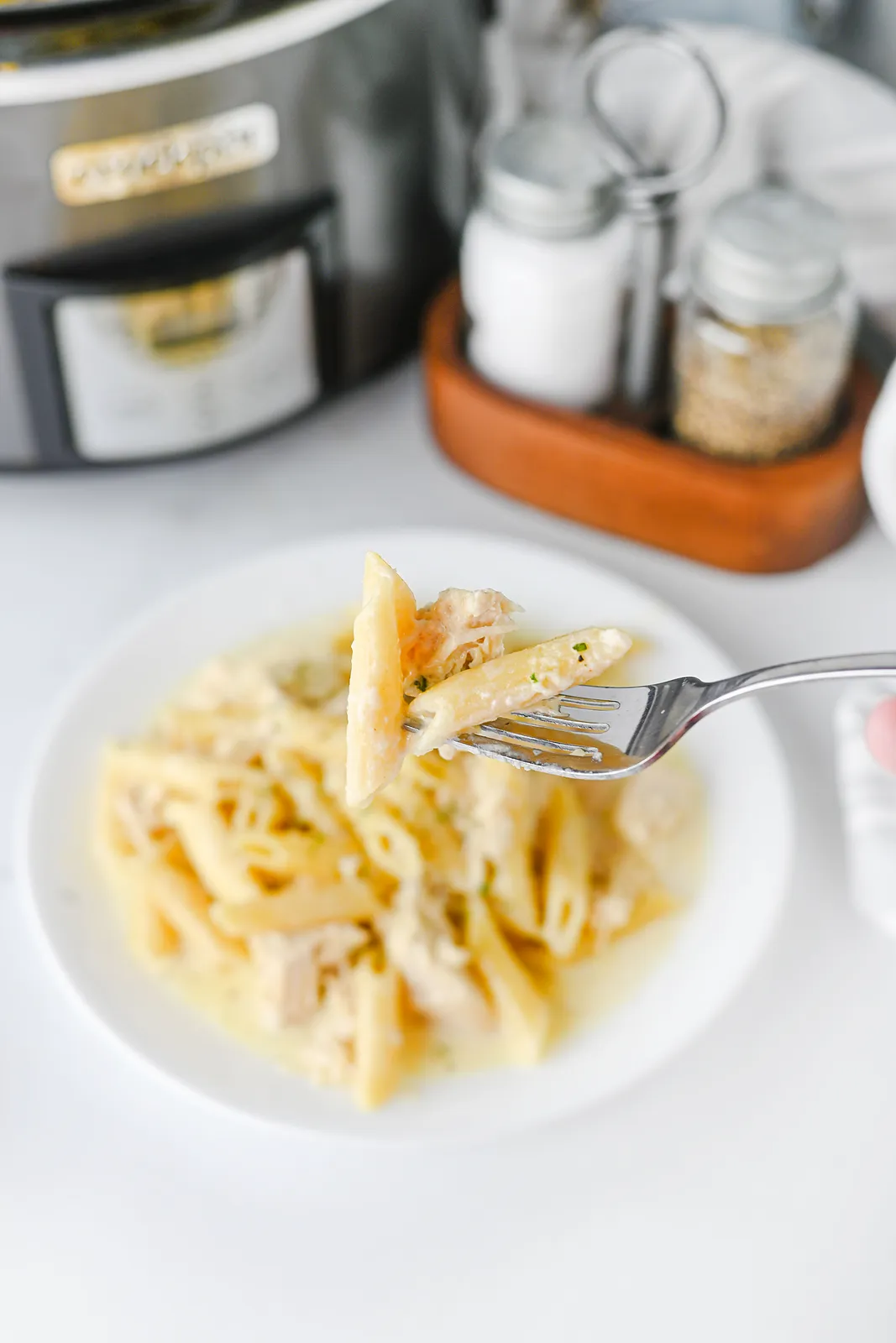 A forkful of penne coated in a silky Parmesan cream sauce